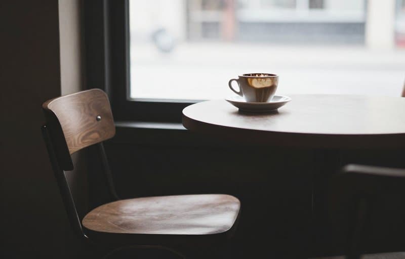 An empty chair at a cafe table with a half-finished coffee left behind, illustrating a subscriber who let a subscription price increase lapse and did not renew