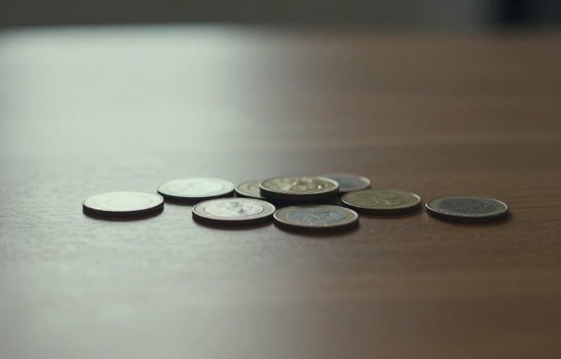 Des pièces glissant du bord d'une table vers l'ombre, illustrant comment un remboursement Google Play est soustrait du paiement d'un développeur