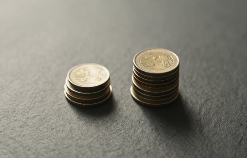 スレート面に置かれた 2 つの不均等な硬貨の山。開発者とストアの間で注文の価値を分け合う部分返金を表しています